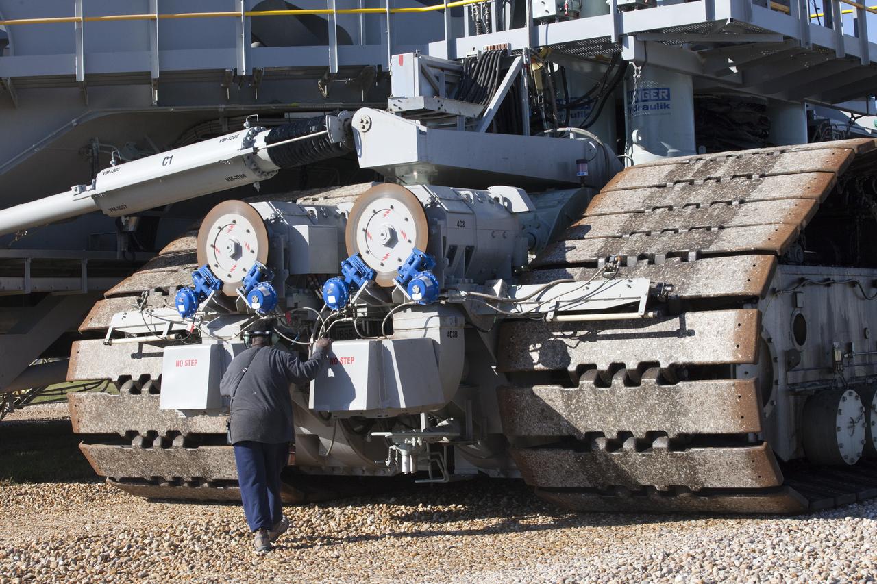 A ground support technician checks the new hydraulic cylinders on crawler-transporter 2 (CT-2) as the vehicle moves slowly along the crawlerway toward the Vehicle Assembly Building at NASA's Kennedy Space Center in Florida. The crawler took a trip to the Pad A/B split to test upgrades recently completed that will allow the giant vehicle to handle the load of the agency's Space Launch System rocket and Orion spacecraft atop the mobile launcher. The Ground Systems Development and Operations Program oversaw upgrades to the 50-year-old CT-2. New generators, gear assemblies, jacking, equalizing and leveling (JEL) hydraulic cylinders, roller bearings and brakes were installed, and other components were upgraded to prepare for Exploration Mission 1. 