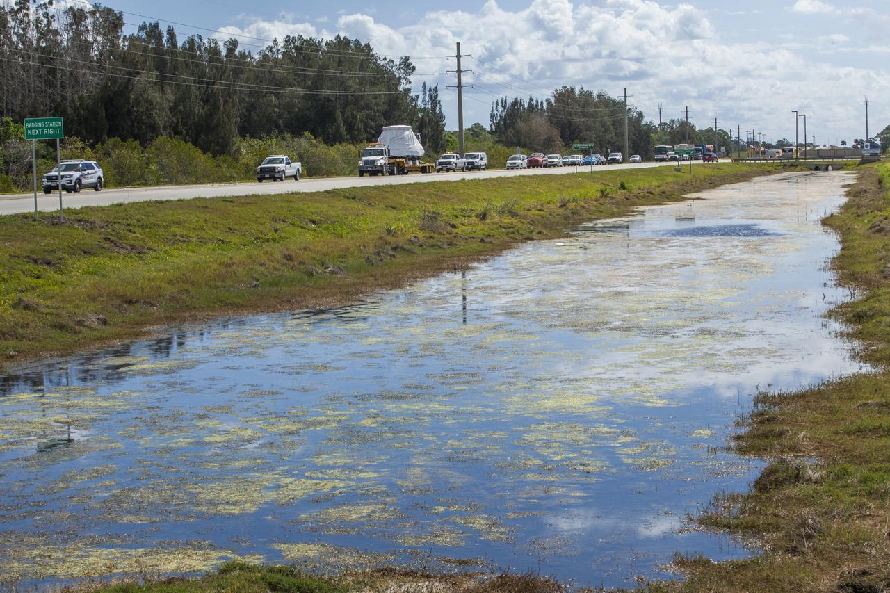 The Orion crew module from Exploration Flight Test 1 is transported west along the NASA Causeway toward NASA's Kennedy Space Center Visitor Complex in Florida. The crew module will be delivered to the IMAX Theater where it will be prepared for display in the NASA Now exhibit. The Orion spacecraft launched atop a United Launch Alliance Delta IV rocket Dec. 5, 2014, from Space Launch Complex 37 at Cape Canaveral Air Force Station. The spacecraft built for humans traveled 3,604 miles above Earth and splashed down about 4.5 hours later in the Pacific Ocean. 