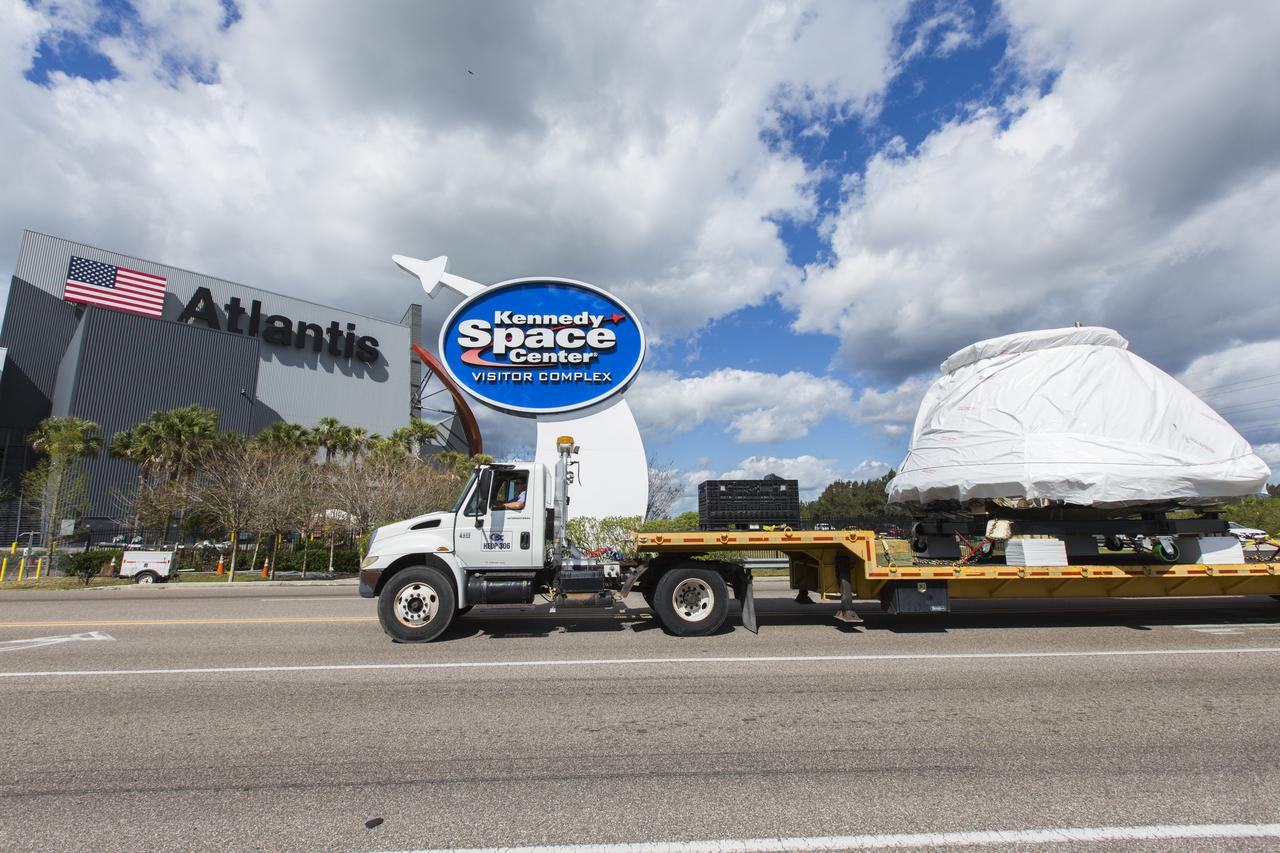 The Orion crew module from Exploration Flight Test 1 arrives at the entrance to NASA's Kennedy Space Center Visitor Complex in Florida. The crew module, secured on ground support equipment atop a flatbed truck, will be delivered to the IMAX Theater where it will be prepared for display in the NASA Now exhibit. The Orion spacecraft launched atop a United Launch Alliance Delta IV rocket Dec. 5, 2014, from Space Launch Complex 37 at Cape Canaveral Air Force Station. The spacecraft built for humans traveled 3,604 miles above Earth and splashed down about 4.5 hours later in the Pacific Ocean. 