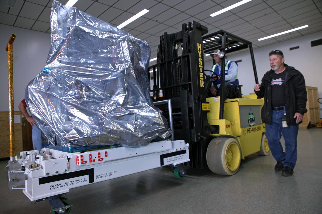 Technicians use a Hyster forklift to move the Multiple User System for Earth Sensing, or MUSES, payload out of the Space Station Processing Facility high bay at NASA's Kennedy Space Center in Florida. MUSES will be delivered to the International Space Station aboard the SpaceX Dragon cargo carrier on the company’s 11th commercial resupply services mission to the space station. MUSES, developed by Teledyne Brown, is part of the company's new commercial space-based digital imaging business. MUSES hosts earth-viewing instruments, such as high-resolution digital cameras, hyperspectral imagers, and provides precision pointing and other accommodations.