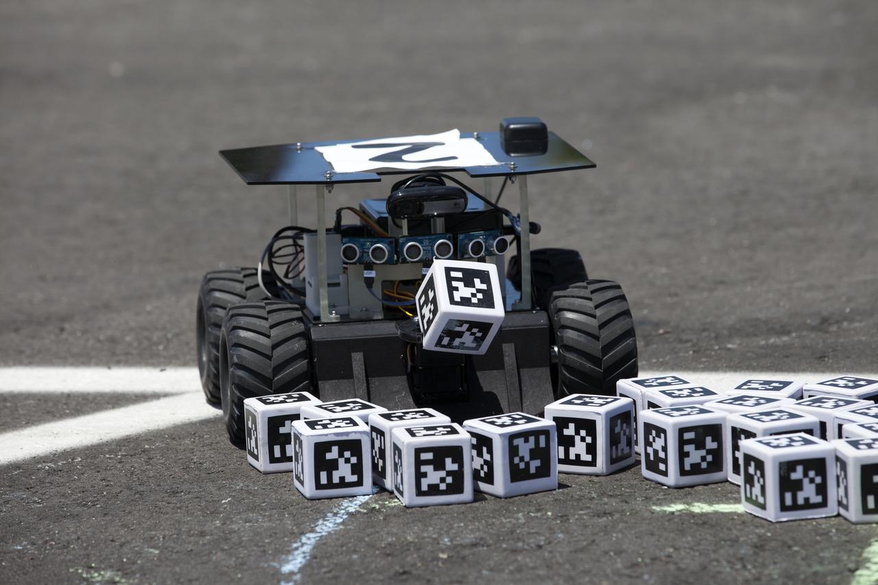 A Swarmie robot finds a "resource" cube marked with an AprilTag, similar to a barcode. In the Swarmathon competition at the Kennedy Space Center Visitor Complex, students were asked to develop computer code for the small robots, programming them to look for "resources" in the form of cubes with AprilTags.