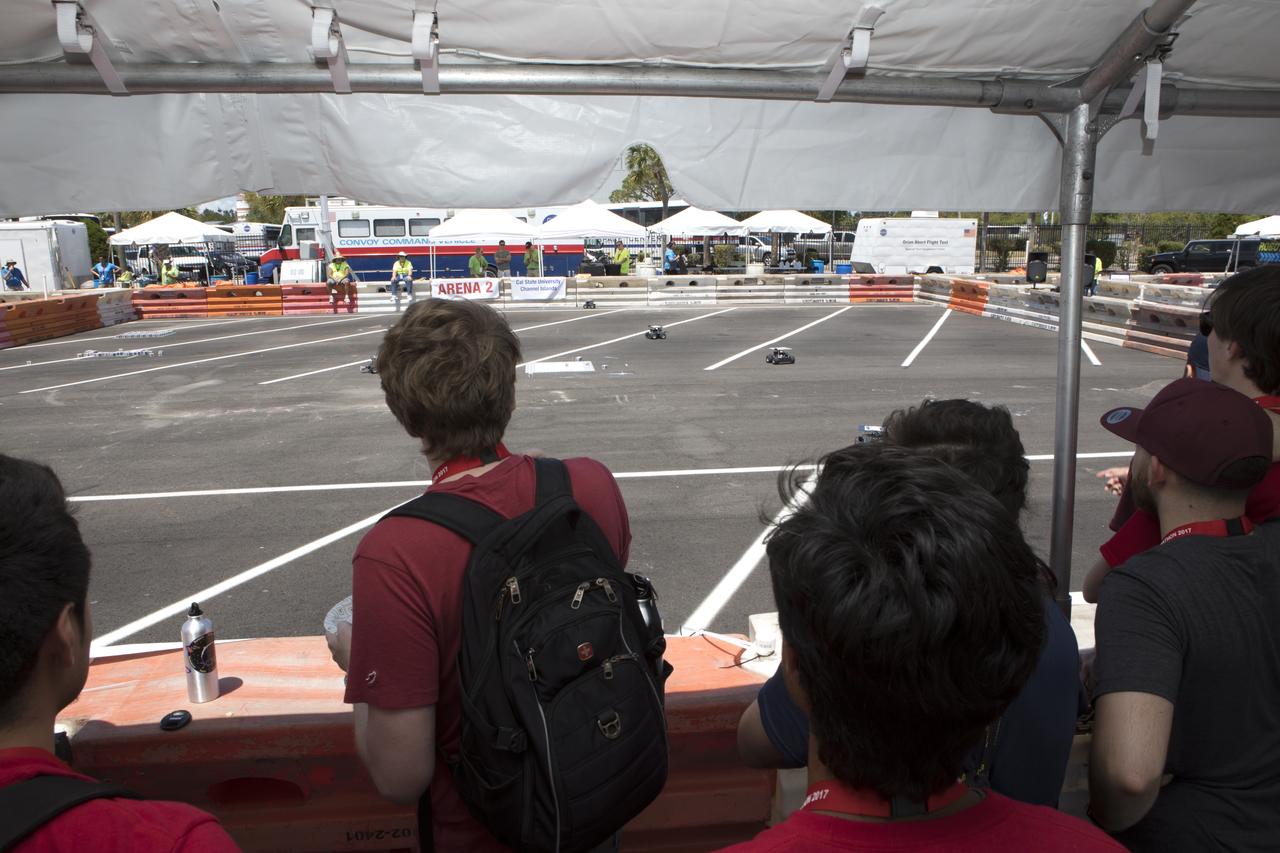 At the Kennedy Space Center Visitor Complex, students monitor progress as their Swarmie robots as they search for "resources." The goal is for the robots to pick up cubes with AprilTags, which are similar to bar codes. The Swarmies then move the cubes to a white square in the center of the completion arena. The small, four-wheeled robots are designed to effectively and efficiently locate hidden resources while astronauts explore distant destinations such as the moon or Mars.
