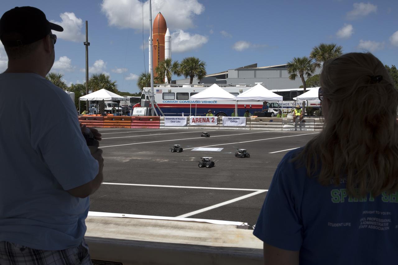 At the Kennedy Space Center Visitor Complex, students monitor progress as their Swarmie robots as they search for "resources." The goal is for the robots to pick up cubes with AprilTags, which are similar to bar codes. The Swarmies then move the cubes to a white square in the center of the completion arena. The small, four-wheeled robots are designed to effectively and efficiently locate hidden resources while astronauts explore distant destinations such as the moon or Mars.