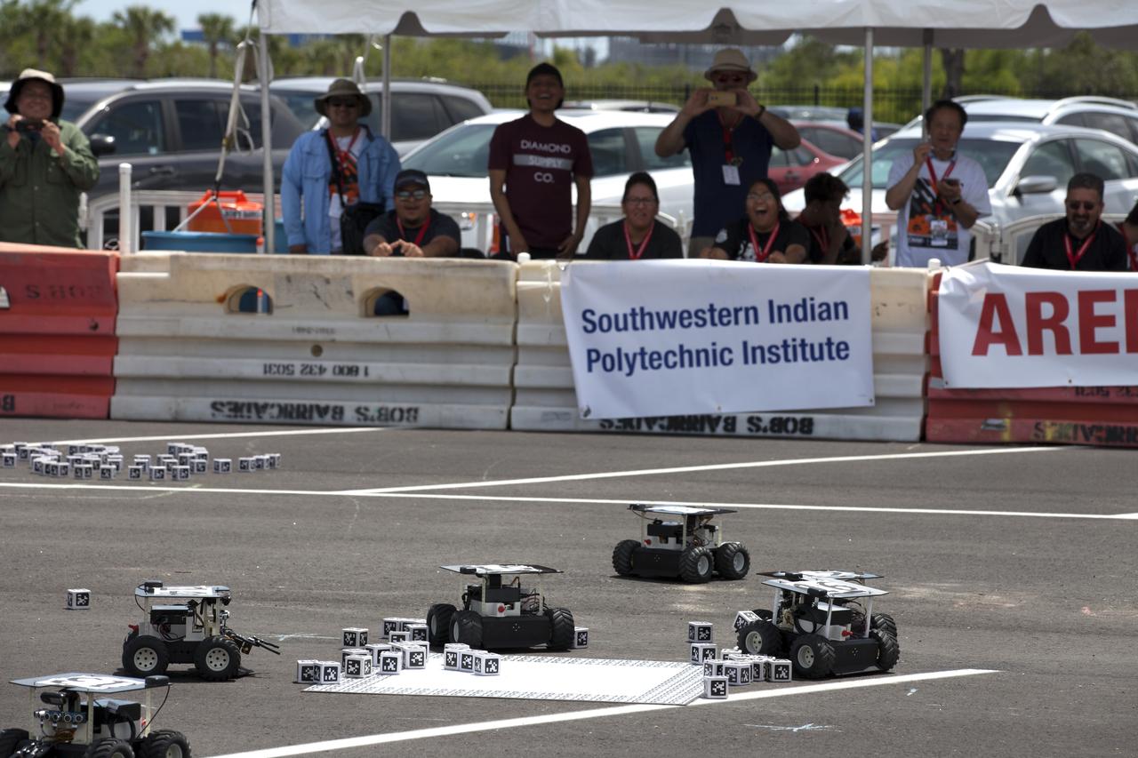 During the final round of the Swarmathon competition at the Kennedy Space Center Visitor Complex, Students from Southwestern Indian Polytechnic Institute (SIPI) in Albuquerque, New Mexico, watch their robots as they look for cubes identified by their AprilTags, similar to a barcodes. The Swarmies were programed to deliver the cubes to a "home" square in the middle of a competition arena. SIPI captured first place in the competition winning a $5,000 cash prize.