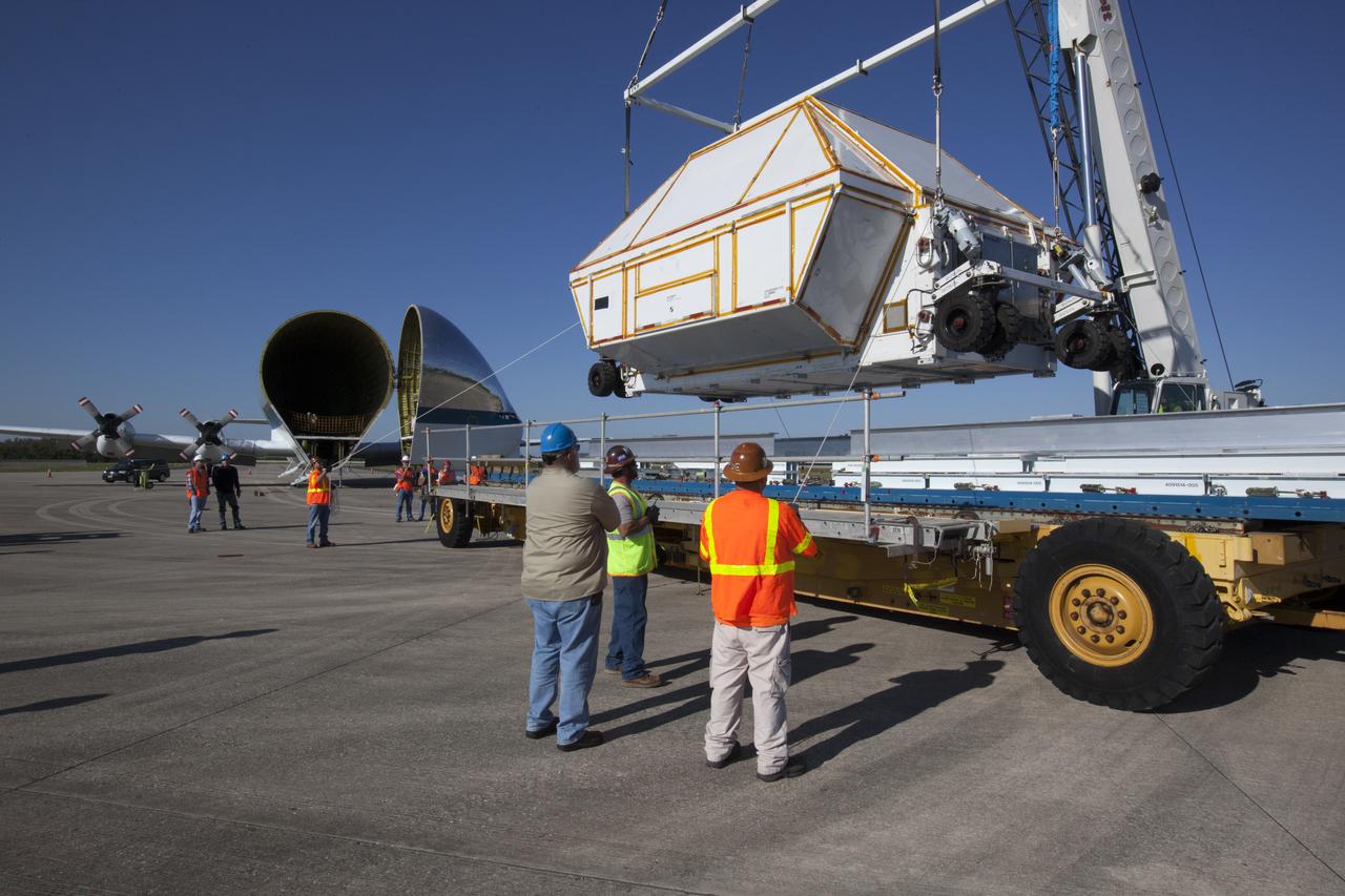 The Orion Exploration Mission-1 (EM-1) structural test article, secured inside its transport container, is lifted up by crane from its transport vehicle at the Shuttle Landing Facility at NASA's Kennedy Space Center in Florida. The test article will be loaded into NASA's Super Guppy aircraft, in view at left, and transported to Lockheed Martin's Denver facility for testing. The Orion spacecraft will launch atop NASA’s Space Launch System rocket on EM-1, its first deep space mission. 