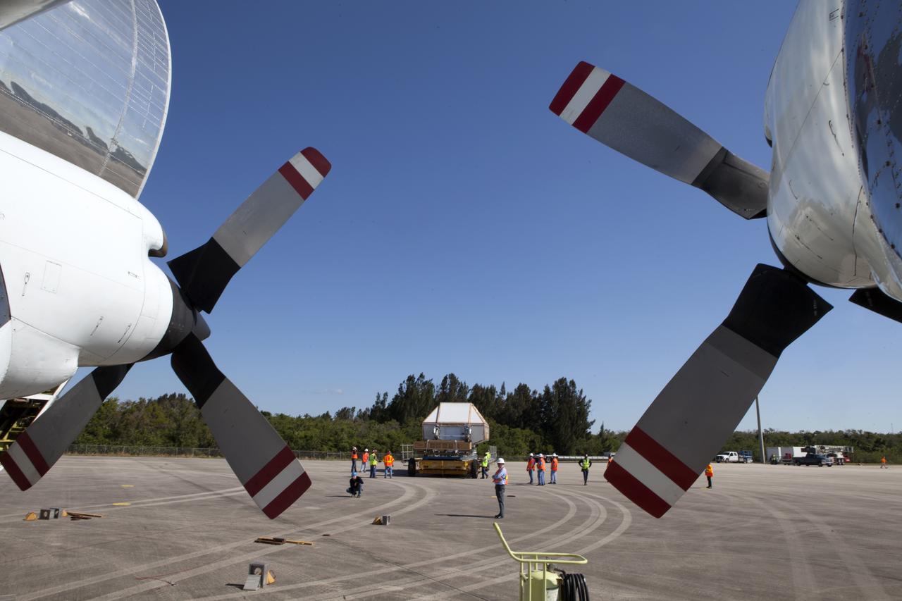 Two of the four propellers and engines of NASA's Super Guppy aircraft are in view at the Shuttle Landing Facility at NASA's Kennedy Space Center in Florida. The Orion Exploration Mission-1 (EM-1) structural test article, secured inside its transport container, will be loaded into the Super Guppy for transport to Lockheed Martin's Denver facility where it will undergo testing. The Orion spacecraft will launch atop NASA’s Space Launch System rocket on EM-1, its first deep space mission. 