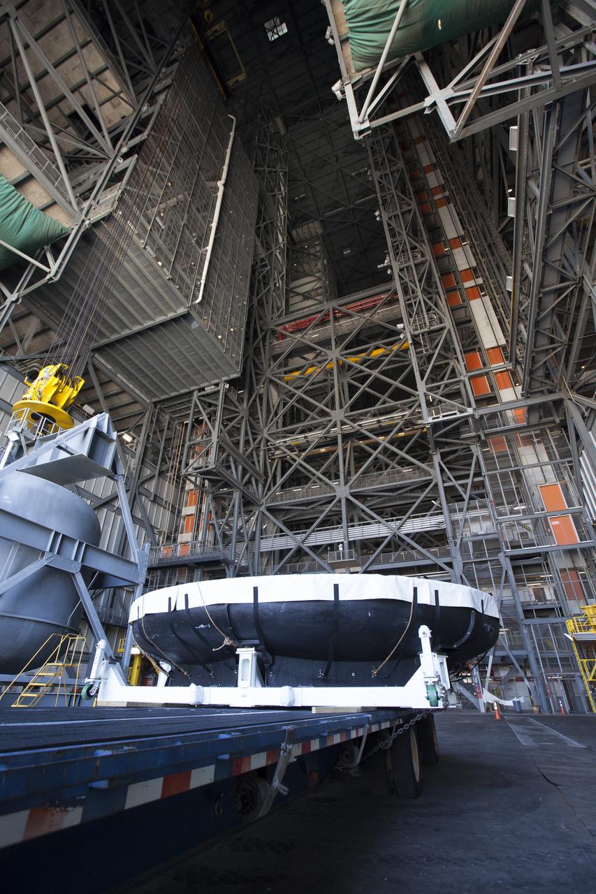 A flatbed truck carrying the Orion heat shield from Exploration Flight Test-1, backs into High Bay 2 in the Vehicle Assembly Building (VAB) at NASA's Kennedy Space Center in Florida. The heat shield was moved from the Launch Abort System Facility. The heat shield is being transferred from the Orion Program to the Ground Systems Development and Operations Program, Landing and Recovery Operations. In the VAB, the heat shield will be integrated with the Orion ground test article and used for future underway recovery testing. 