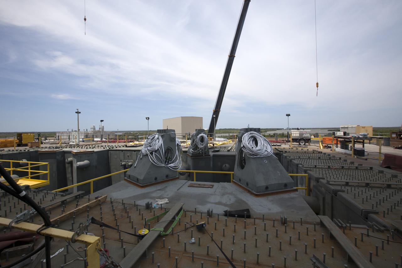 In view are three vehicle support posts installed on the deck of the mobile launcher at NASA's Kennedy Space Center in Florida. A total of eight support posts will be installed to support the load of the Space Launch System's (SLS) solid rocket boosters, with four posts for each of the boosters. The support posts are about five feet tall and each weigh about 10,000 pounds. The posts will structurally support the SLS rocket through T-0 and liftoff, and will drop down before vehicle liftoff to avoid contact with the flight hardware. The Ground Systems Development and Operations Program is overseeing installation of the support posts to prepare for the launch of the Orion spacecraft atop the SLS rocket. 