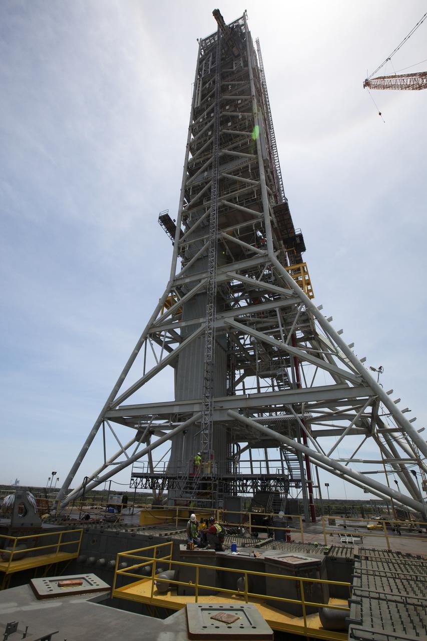 Construction workers on the deck of the mobile launcher at NASA's Kennedy Space Center in Florida, prepare a platform for installation of a vehicle support post. A total of eight support posts will be installed to support the load of the Space Launch System's (SLS) solid rocket boosters, with four posts for each of the boosters. The support posts are about five feet tall and each weigh about 10,000 pounds. The posts will structurally support the SLS rocket through T-0 and liftoff, and will drop down before vehicle liftoff to avoid contact with the flight hardware. The Ground Systems Development and Operations Program is overseeing installation of the support posts to prepare for the launch of the Orion spacecraft atop the SLS rocket. 