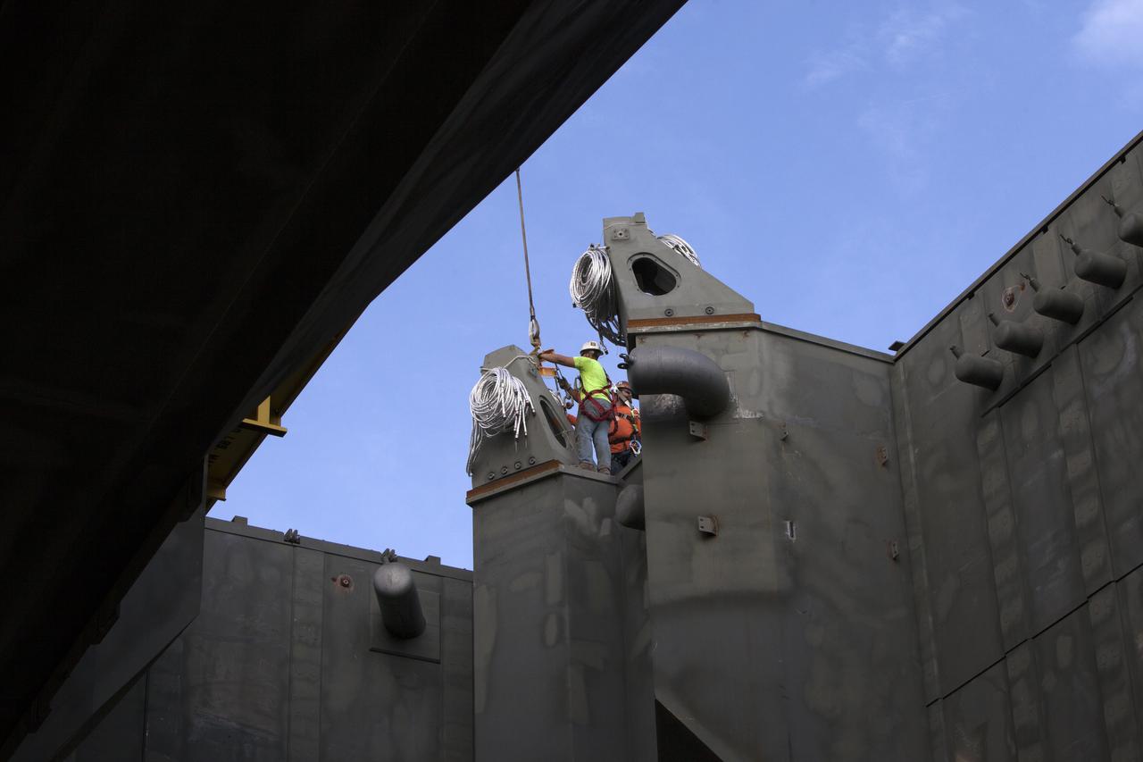 At NASA's Kennedy Space Center in Florida, construction workers on the deck of the mobile launcher install the final four vehicle support posts. A total of eight support posts are being installed to support the load of the Space Launch System's (SLS) solid rocket boosters, with four posts for each of the boosters. The support posts are about five feet tall and each weigh about 10,000 pounds. The posts will structurally support the SLS rocket through T-0 and liftoff, and will drop down before vehicle liftoff to avoid contact with the flight hardware. The Ground Systems Development and Operations Program is overseeing installation of the support posts to prepare for the launch of the Orion spacecraft atop the SLS rocket. 
