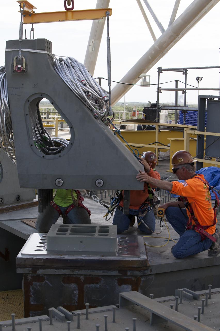 Construction workers on the deck of the mobile launcher at NASA's Kennedy Space Center in Florida, prepare to install a vehicle support post. A total of eight support posts are being installed to support the load of the Space Launch System's (SLS) solid rocket boosters, with four posts for each of the boosters. The support posts are about five feet tall and each weigh about 10,000 pounds. The posts will structurally support the SLS rocket through T-0 and liftoff, and will drop down before vehicle liftoff to avoid contact with the flight hardware. The Ground Systems Development and Operations Program is overseeing installation of the support posts to prepare for the launch of the Orion spacecraft atop the SLS rocket. 