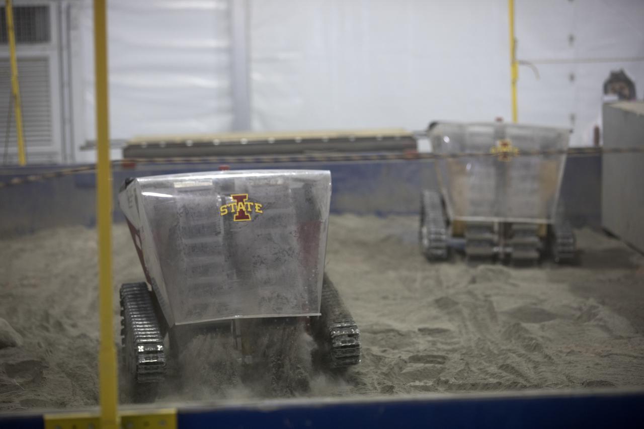 Twin mining robots from the University of Iowa dig in a supersized sandbox filled with BP-1, or simulated Martian soil, during NASA's 8th Annual Robotic Mining Competition at the Kennedy Space Center Visitor Complex in Florida. More than 40 student teams from colleges and universities around the U.S. are  using their uniquely-designed mining robots to dig in a supersized sandbox filled with BP-1, or simulated Martian soil, and participate in other competition requirements. The Robotic Mining Competition is a NASA Human Exploration and Operations Mission Directorate project designed to encourage students in science, technology, engineering and math, or STEM fields. The project provides a competitive environment to foster innovative ideas and solutions that could be used on NASA's Journey to Mars.