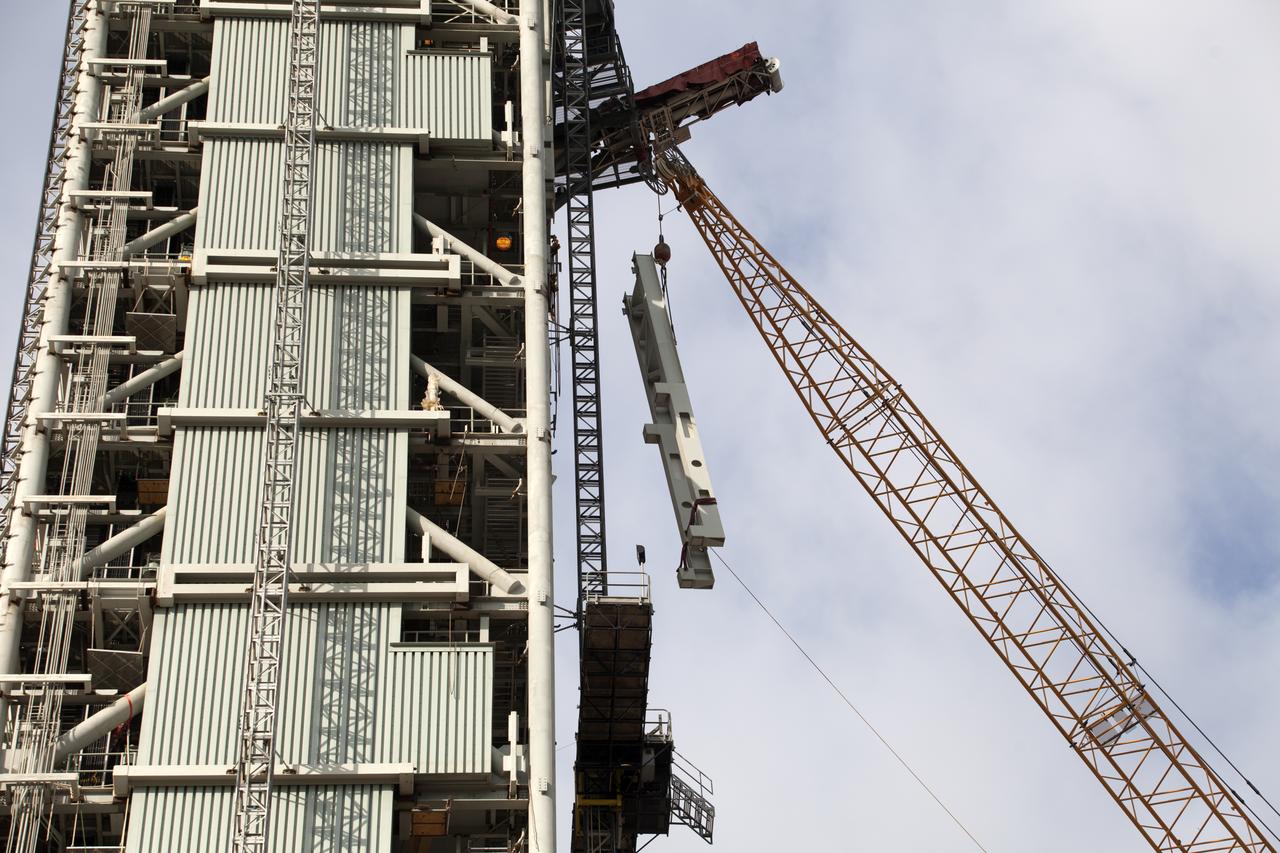 Cranes and rigging are being used to lift up the Core Stage Forward Skirt Umbilical (CSFSU) for installation on the mobile launcher tower at NASA's Kennedy Space Center in Florida. The mobile launcher tower will be equipped with a number of lines, called umbilicals that will connect to the Space Launch System (SLS) rocket and Orion spacecraft for Exploration Mission-1 (EM-1). The CSFSU will be located at about the 180-foot level on the tower, above the liquid oxygen tank. The CSFSU is an umbilical that will swing into position to provide connections to the core stage forward skirt of the SLS rocket, and then swing away before launch. Its main purpose is to provide conditioned air/GN2 to the SLS core stage forward skirt cavity. The Ground Systems Development and Operations Program is overseeing installation of the umbilicals.