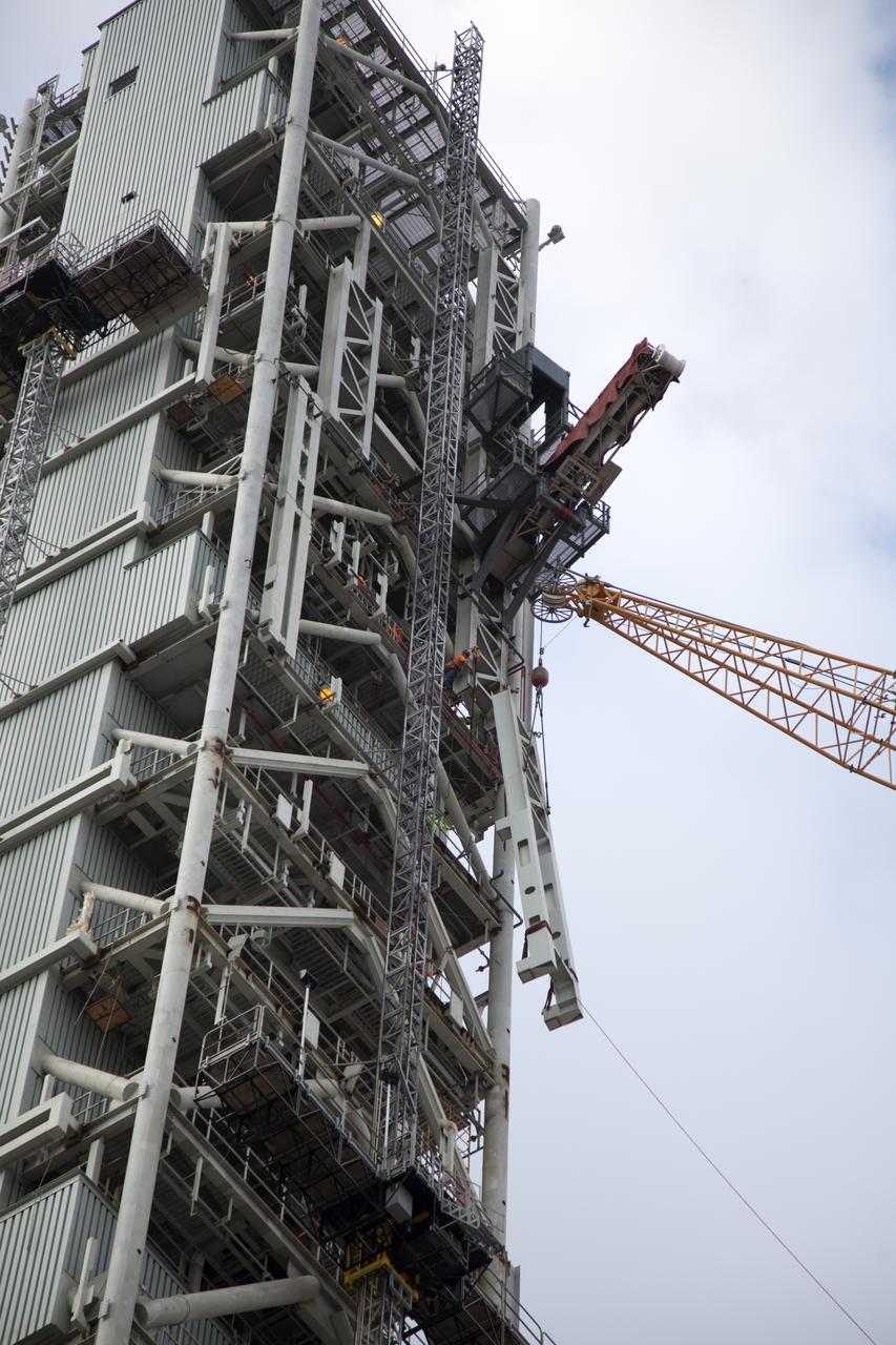 Seeming to hang in midair, the Core Stage Forward Skirt Umbilical (CSFSU) is lifted high up by crane for installation on the mobile launcher tower at NASA's Kennedy Space Center in Florida. The mobile launcher tower will be equipped with a number of lines, called umbilicals that will connect to the Space Launch System rocket and Orion spacecraft for Exploration Mission-1 (EM-1). The CSFSU will be located at about the 180-foot level on the tower, above the liquid oxygen tank. The CSFSU is an umbilical that will swing into position to provide connections to the core stage forward skirt of the SLS rocket, and then swing away before launch. Its main purpose is to provide conditioned air/GN2 to the SLS core stage forward skirt cavity. The Ground Systems Development and Operations Program is overseeing installation of the umbilicals.