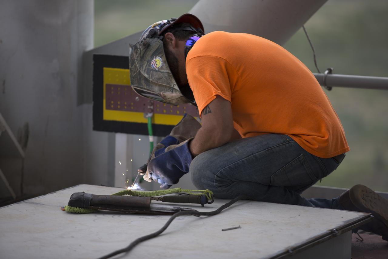 A construction worker welds a metal part during installation of the Core Stage Forward Skirt Umbilical on the mobile launcher tower at NASA's Kennedy Space Center in Florida. The mobile launcher tower will be equipped with a number of lines, called umbilicals that will connect to the Space Launch System (SLS) rocket and Orion spacecraft for Exploration Mission-1 (EM-1). The CSFSU will be located at about the 180-foot level on the tower, above the liquid oxygen tank. The CSFSU is an umbilical that will swing into position to provide connections to the core stage forward skirt of the SLS rocket, and then swing away before launch. Its main purpose is to provide conditioned air/GN2 to the SLS core stage forward skirt cavity. The Ground Systems Development and Operations Program is overseeing installation of the umbilicals.
