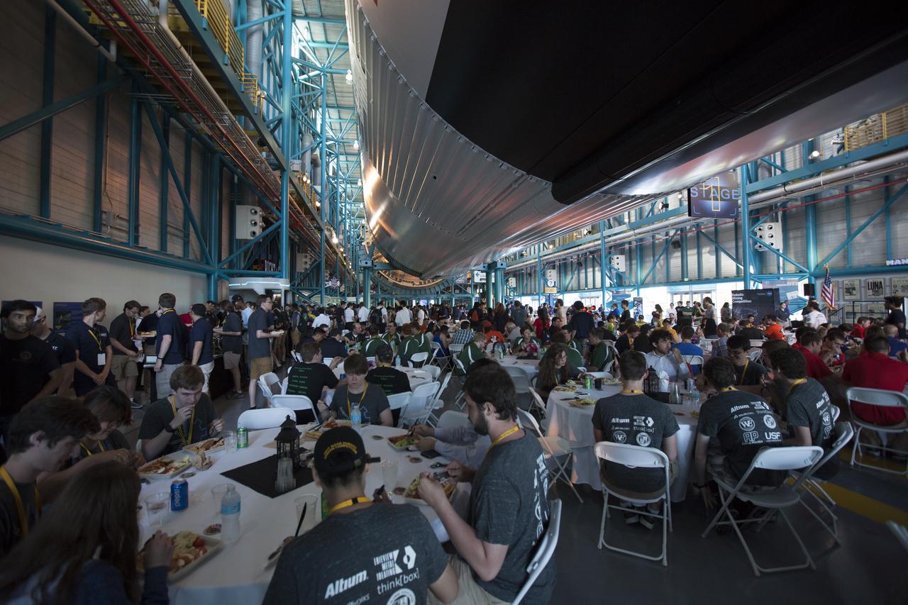 Inside the Apollo-Saturn V Center at NASA's Kennedy Space Center Visitor Complex in Florida, teams from the 8th Annual Robotic Mining Competition eat dinner before the awards ceremony begins. More than 40 student teams from colleges and universities around the U.S. used their mining robots to dig in a supersized sandbox filled with BP-1, or simulated Martian soil, and participated in other competition requirements, May 22-26 at the visitor complex. The Robotic Mining Competition is a NASA Human Exploration and Operations Mission Directorate project designed to encourage students in science, technology, engineering and math, or STEM fields. The project provides a competitive environment to foster innovative ideas and solutions that could be used on NASA's Journey to Mars. 
