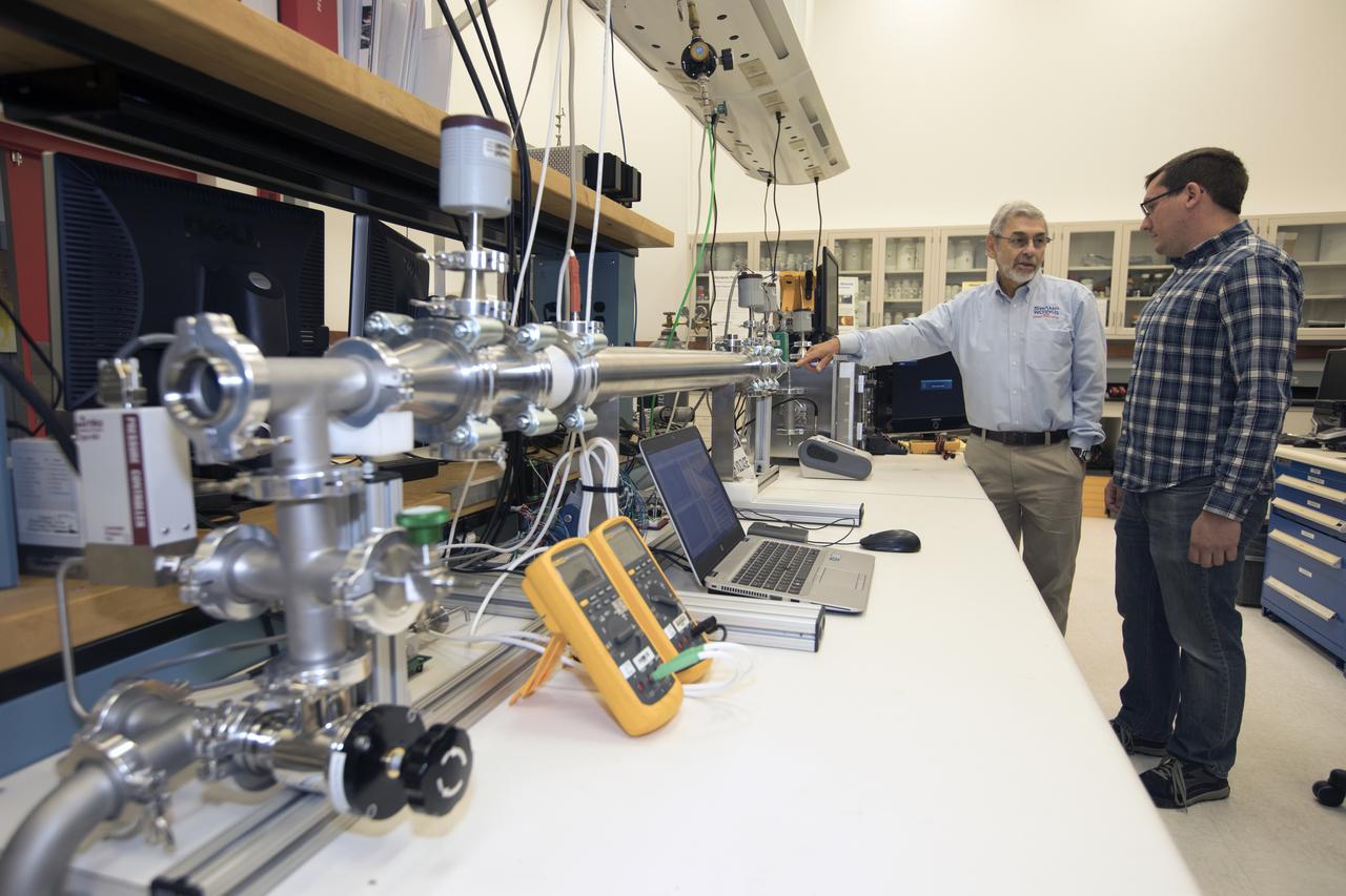 Dr. Carlos Calle, lead scientist in the Kennedy Space Center's Electrostatics and Surface Physics Laboratory, left, and Jay Phillips, a research physicist, are modifying an electrostatic precipitator to help remove dust from a simulated Martian atmosphere. NASA's Journey to Mars requires cutting-edge technologies to solve the problems explorers will face on the Red Planet. Scientists are developing some of the needed solutions by adapting a device to remove the ever-present dust from valuable elements in the Martian atmosphere. Those commodities include oxygen, water and methane.