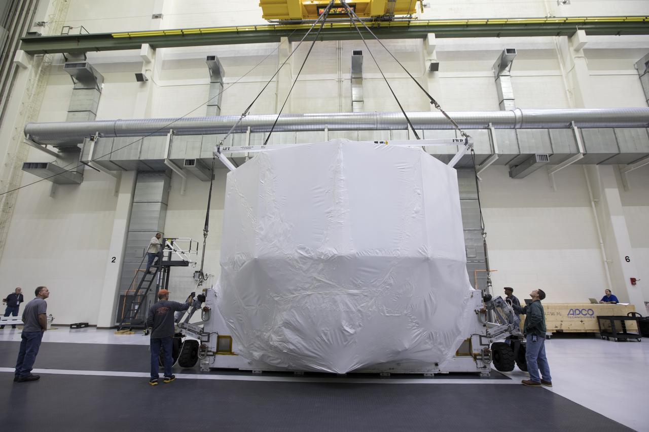 The Orion service module structural test article for Exploration Mission-1 (EM-1), built by the European Space Agency, is prepared for shipment to Lockheed Martin's Denver facility to undergo testing. Inside the Neil Armstrong Operations and Checkout Building high bay at NASA's Kennedy Space Center in Florida, workers secure the protective covering around the module and a crane is used to lower it onto a stand. The Orion spacecraft will launch atop the agency's Space Launch System rocket on EM-1 in 2019.