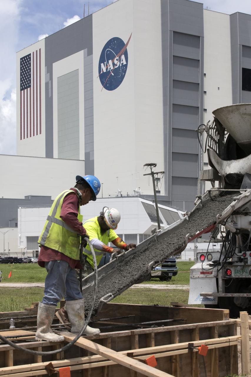 Across from the Vehicle Assembly Building at NASA's Kennedy Space Center in Florida, cement is poured as part of a construction project to upgrade the turn basin wharf. The work includes driving multiple precast concrete piles to a depth of about 70 feet to accommodate arrival of the core stage for the agency's Space Launch System (SLS) rocket. When the stage for NASA's SLS departs the Michoud Assembly Facility in New Orleans, it will be shipped by the agency's modified barge to the Launch Complex 39 turn basin.