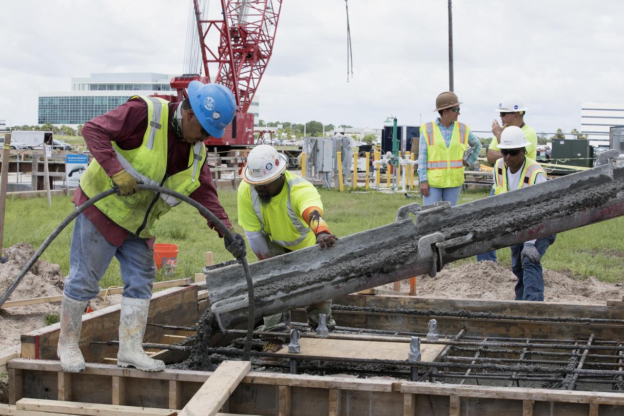 Across from the Vehicle Assembly Building at NASA's Kennedy Space Center in Florida, cement is poured as part of a construction project to upgrade the turn basin wharf. The work includes driving multiple precast concrete piles to a depth of about 70 feet to accommodate arrival of the core stage for the agency's Space Launch System (SLS) rocket. When the stage for NASA's SLS departs the Michoud Assembly Facility in New Orleans, it will be shipped by the agency's modified barge to the Launch Complex 39 turn basin.