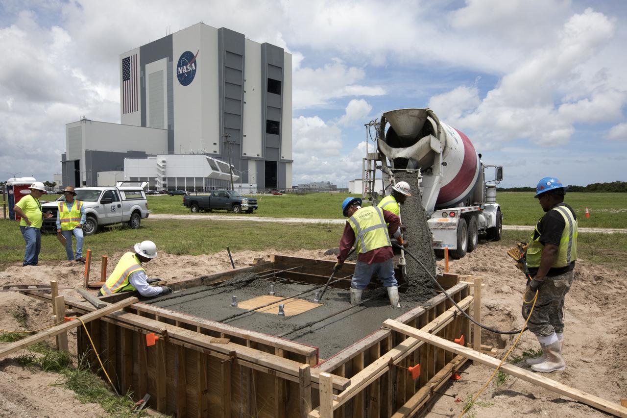 Across from the Vehicle Assembly Building at NASA's Kennedy Space Center in Florida, cement is poured as part of a construction project to upgrade the turn basin wharf. The work includes driving multiple precast concrete piles to a depth of about 70 feet to accommodate arrival of the core stage for the agency's Space Launch System (SLS) rocket. When the stage for NASA's SLS departs the Michoud Assembly Facility in New Orleans, it will be shipped by the agency's modified barge to the Launch Complex 39 turn basin.
