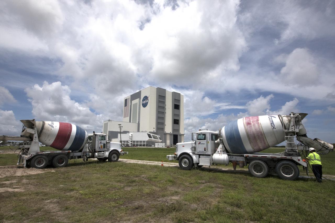 Across from the Vehicle Assembly Building at NASA's Kennedy Space Center in Florida, cement trucks stand by to support a construction project to upgrade the turn basin wharf. The work includes driving multiple precast concrete piles to a depth of about 70 feet to accommodate arrival of the core stage for the agency's Space Launch System (SLS) rocket. When the stage for NASA's SLS departs the Michoud Assembly Facility in New Orleans, it will be shipped by the agency's modified barge to the Launch Complex 39 turn basin.