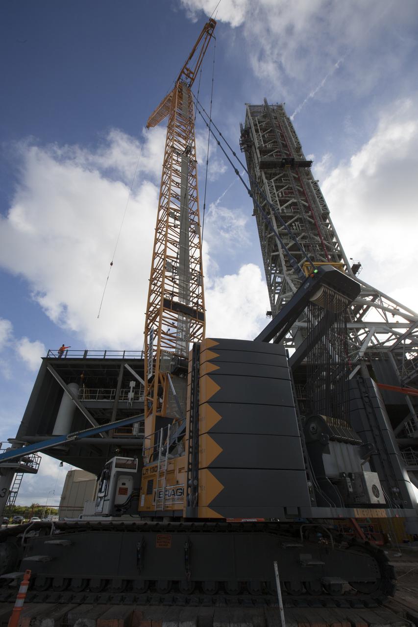 Just north of the Vehicle Assembly Building at NASA's Kennedy Space Center in Florida, a crane is prepared to lift the core stage forward skirt umbilical) for installation onto the mobile launcher. The mobile launcher is designed to support the assembly, testing and check-out of the agency's Space Launch System (SLS) rocket and the Orion spacecraft.
