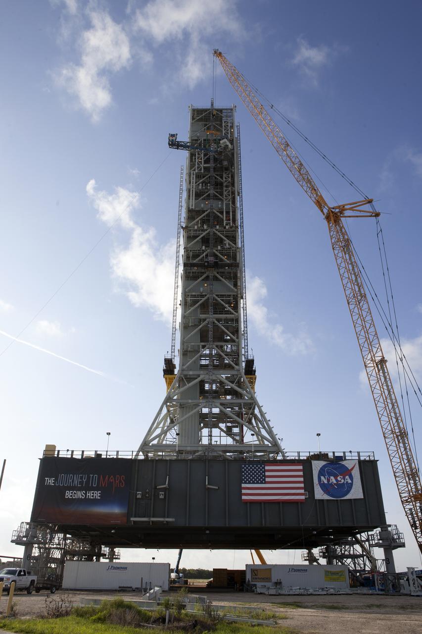 Just north of the Vehicle Assembly Building at NASA's Kennedy Space Center in Florida, a crane lifts the core stage forward skirt umbilical for installation onto the mobile launcher. The mobile launcher is designed to support the assembly, testing and check-out of the agency's Space Launch System (SLS) rocket and the Orion spacecraft.