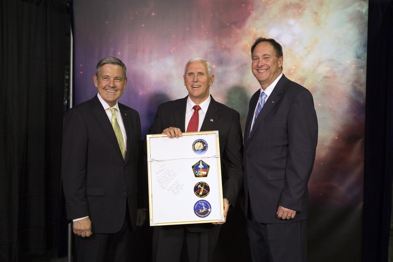 Kennedy Space Center Bob Cabana, left, and NASA's Acting Administrator Robert Lightfoot, right present Vice President Mike Pence with a framed plaque. On the back of the plaque are patches from each of Cabana's four space shuttle mission, STS-88, STS-53, STS-65, STS-41, and an inscription thanking the Vice President for his support of NASA. During his visit to Kennedy, the Vice President spoke inside the iconic Vehicle Assembly Building, where he thanked employees for advancing American leadership in space. 