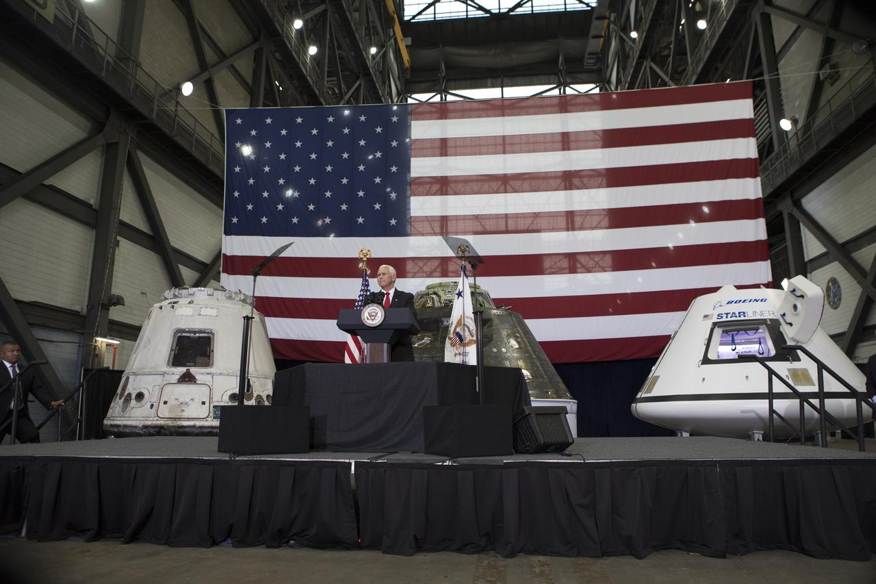 Vice President Mike Pence speaks before an audience of NASA leaders, U.S. and Florida government officials, and employees inside the Vehicle Assembly Building at NASA's Kennedy Space Center in Florida. Pence thanked employees for advancing American leadership in space. Behind the podium are, from the left, a flown SpaceX Dragon capsule, the Orion spacecraft flown on Exploration Flight test-1 in 2014, and a mockup of Boeing's CST-100 Starliner. During his visit to Kennedy, the Vice President also toured several facilities highlighting the public-private partnerships, as both NASA and commercial companies prepare to launch American astronauts from the multi-user spaceport.