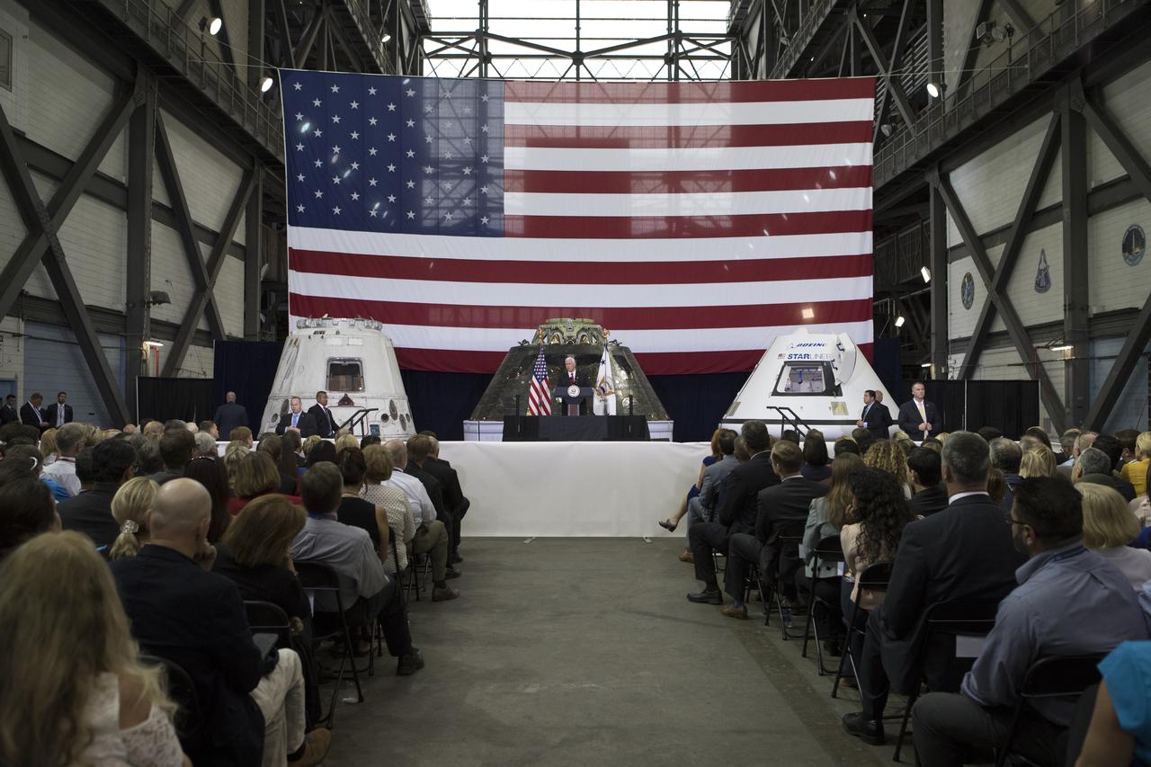 Vice President Mike Pence speaks before an audience of NASA leaders, U.S. and Florida government officials, and employees inside the Vehicle Assembly Building at NASA's Kennedy Space Center in Florida. Pence thanked employees for advancing American leadership in space. Behind the podium are, from the left, a flown SpaceX Dragon capsule, the Orion spacecraft flown on Exploration Flight test-1 in 2014, and a mockup of Boeing's CST-100 Starliner. During his visit to Kennedy, the Vice President also toured several facilities highlighting the public-private partnerships, as both NASA and commercial companies prepare to launch American astronauts from the multi-user spaceport.
