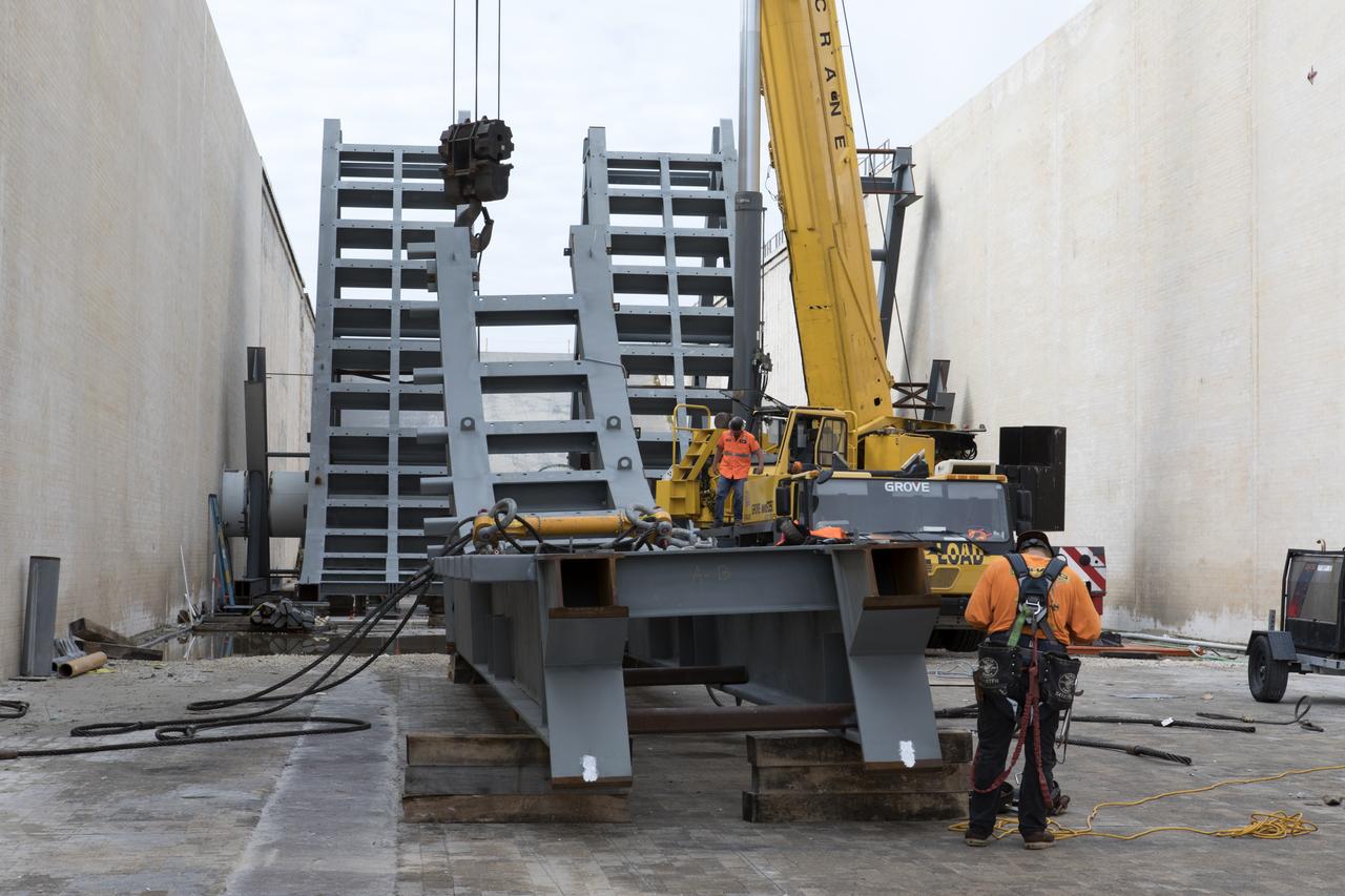 At Launch Pad 39B at NASA's Kennedy Space Center in Florida, construction workers position large segments of the support hardware for a new flame deflector in the flame trench. The new flame deflector will be positioned about six feet south of the shuttle-era flame deflector’s position. During liftoff of NASA’s Space Launch System, the rocket’s flame and energy will be diverted to the north side of the flame trench. The north side of the deflector will be protected by a NASA standard coating. The south side of the deflector will not be slanted and will have no lining. The new design will provide easier access for inspection, maintenance and repair. The Ground Systems Development and Operations (GSDO) Program at Kennedy is managing the installation of the flame deflector for Exploration Mission 1, deep space missions, and NASA's Journey to Mars. 