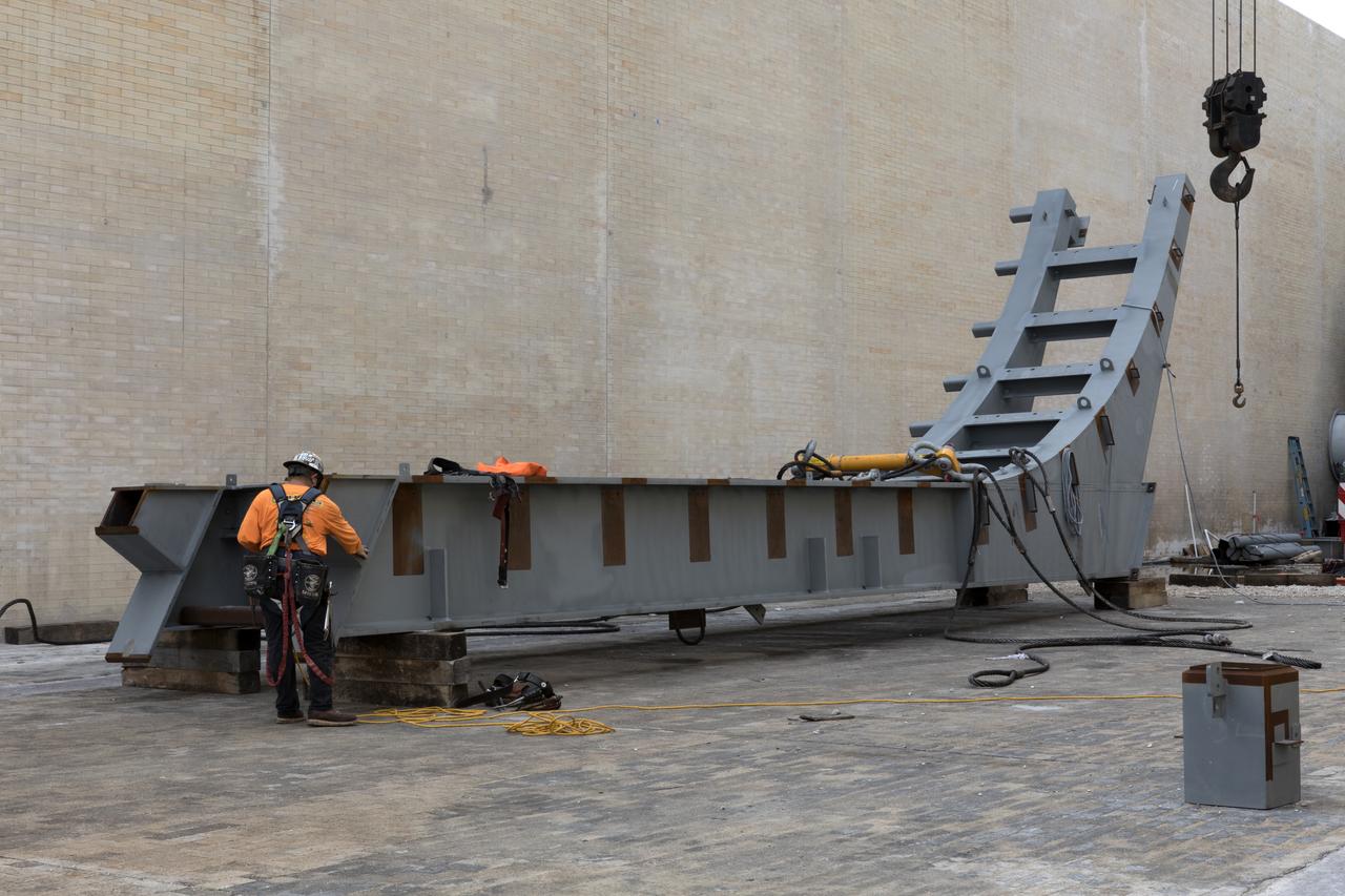 At Launch Pad 39B at NASA's Kennedy Space Center in Florida, a construction worker prepares a large segments of the support hardware for a new flame deflector to be lifted into place in the flame trench. The new flame deflector will be positioned about six feet south of the shuttle-era flame deflector’s position. During liftoff of NASA’s Space Launch System, the rocket’s flame and energy will be diverted to the north side of the flame trench. The north side of the deflector will be protected by a NASA standard coating. The south side of the deflector will not be slanted and will have no lining. The new design will provide easier access for inspection, maintenance and repair. The Ground Systems Development and Operations (GSDO) Program at Kennedy is managing the installation of the flame deflector for Exploration Mission 1, deep space missions, and NASA's Journey to Mars.