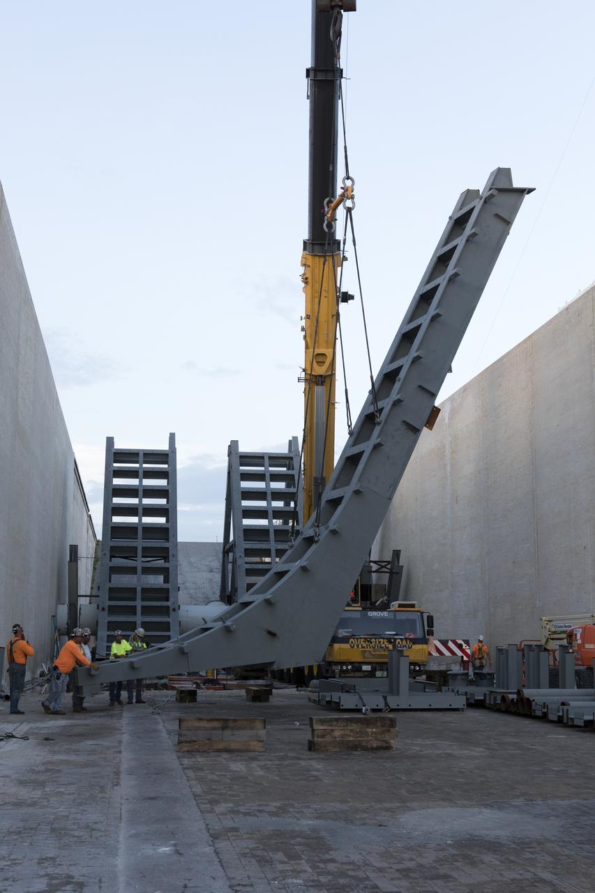 At Launch Pad 39B at NASA's Kennedy Space Center in Florida, a crane is used to move one of the large segments of the support hardware for a new flame deflector and position it in the flame trench. The new flame deflector will be positioned about six feet south of the shuttle-era flame deflector’s position. During liftoff of NASA’s Space Launch System, the rocket’s flame and energy will be diverted to the north side of the flame trench. The north side of the deflector will be protected by a NASA standard coating. The south side of the deflector will not be slanted and will have no lining. The new design will provide easier access for inspection, maintenance and repair. The Ground Systems Development and Operations (GSDO) Program at Kennedy is managing the installation of the flame deflector for Exploration Mission 1, deep space missions, and NASA's Journey to Mars. 
