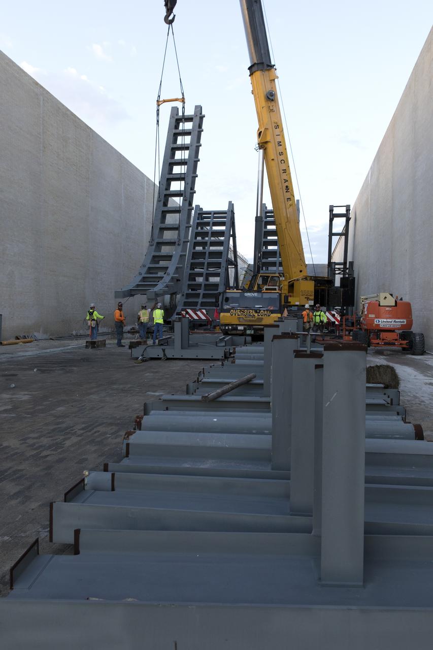 At Launch Pad 39B at NASA's Kennedy Space Center in Florida, a crane is used to move one of the large segments of the support hardware for a new flame deflector and position it in the flame trench. The new flame deflector will be positioned about six feet south of the shuttle-era flame deflector’s position. During liftoff of NASA’s Space Launch System, the rocket’s flame and energy will be diverted to the north side of the flame trench. The north side of the deflector will be protected by a NASA standard coating. The south side of the deflector will not be slanted and will have no lining. The new design will provide easier access for inspection, maintenance and repair. The Ground Systems Development and Operations (GSDO) Program at Kennedy is managing the installation of the flame deflector for Exploration Mission 1, deep space missions, and NASA's Journey to Mars. 