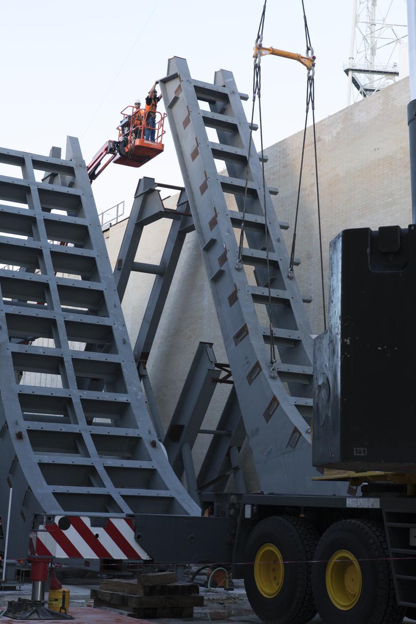 At Launch Pad 39B at NASA's Kennedy Space Center in Florida, construction workers assist as a large segment of the support hardware for a new flame deflector is positioned in the flame trench. The new flame deflector will be positioned about six feet south of the shuttle-era flame deflector’s position. During liftoff of NASA’s Space Launch System, the rocket’s flame and energy will be diverted to the north side of the flame trench. The north side of the deflector will be protected by a NASA standard coating. The south side of the deflector will not be slanted and will have no lining. The new design will provide easier access for inspection, maintenance and repair. The Ground Systems Development and Operations (GSDO) Program at Kennedy is managing the installation of the flame deflector for Exploration Mission 1, deep space missions, and NASA's Journey to Mars. 