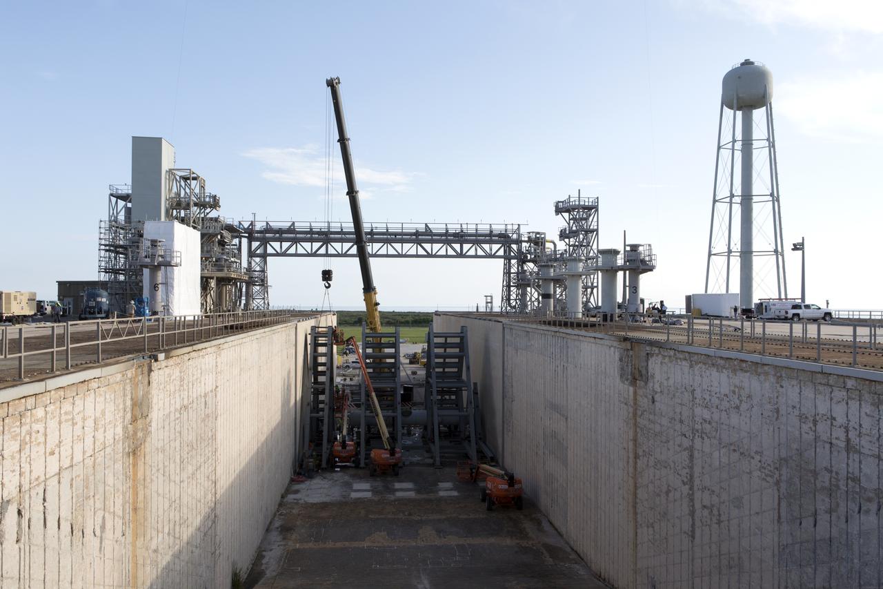 At Launch Pad 39B at NASA's Kennedy Space Center in Florida, cranes lower large segments of the support hardware for a new flame deflector into place in the flame trench. Construction workers weld the structures together. The new flame deflector will be positioned about six feet south of the shuttle-era flame deflector’s position. During liftoff of NASA’s Space Launch System, the rocket’s flame and energy will be diverted to the north side of the flame trench. The north side of the deflector will be protected by a NASA standard coating. The south side of the deflector will not be slanted and will have no lining. The new design will provide easier access for inspection, maintenance and repair. The Ground Systems Development and Operations (GSDO) Program at Kennedy is managing the installation of the flame deflector for Exploration Mission 1, deep space missions, and NASA's Journey to Mars.