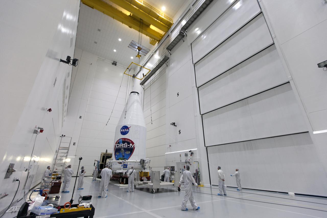 Technicians monitor the progress as NASA's TDRS-M satellite, enclosed in its payload fairing, is lowered onto a transport vehicle inside the Astrotech facility near NASA's Kennedy Space Center in Florida. The TDRS-M is the latest spacecraft destined for the agency's constellation of communications satellites that allows nearly continuous contact with orbiting spacecraft ranging from the International Space Station and Hubble Space Telescope to the array of scientific observatories. Liftoff atop a United Launch Alliance Atlas V rocket is scheduled to take place from Space Launch Complex 41 at Cape Canaveral Air Force Station on Aug. 18 at 8:03 a.m. EDT. 