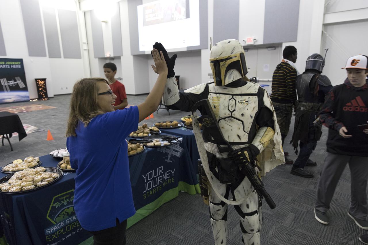 A middle-school student high-fives a Star Wars character from the 501st Legion in the Center for Space Education at NASA’s Kennedy Space Center in Florida. Teams from across the state of Florida were gathered at Kennedy for the finals of the Zero Robotics Middle School Summer Program national championship. The five-week program allows rising sixth- through ninth-graders to write programs for small satellites called SPHERES (Synchronized, Position, Hold, Engage, Reorient, Experimental Satellites). Finalists saw their code tested aboard the International Space Station.