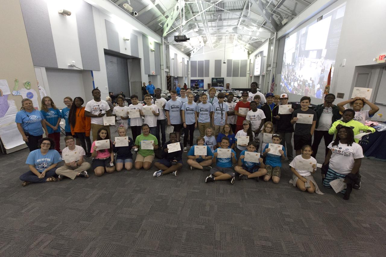Students and their sponsors gather for a commemorative photo in the Center for Space Education at NASA’s Kennedy Space Center in Florida after participating in the finals of the Zero Robotics Middle School Summer Program national championship. The five-week program allows rising sixth- through ninth-graders to write programs for small satellites called SPHERES (Synchronized, Position, Hold, Engage, Reorient, Experimental Satellites). Finalists saw their code tested aboard the International Space Station.