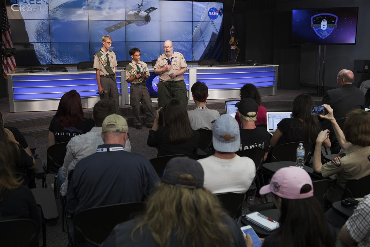 Boy Scouts of America Troop 209 members Andrew Frank, left, Elliot Lee center, and team leader Norman McFarland speak to members of social media in the Kennedy Space Center’s Press Site auditorium. The briefing focused on research planned for launch to the International Space Station. The scientific materials and supplies will be aboard a Dragon spacecraft scheduled for launch from Kennedy’s Launch Complex 39A on Aug. 14 atop a SpaceX Falcon 9 rocket on the company's 12th Commercial Resupply Services mission to the space station.