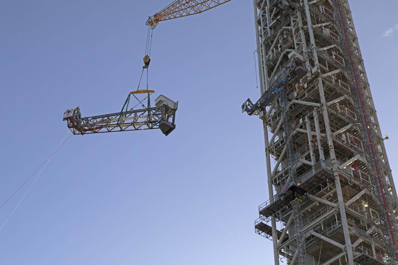 A heavy-lift crane and rigging are used to lift the Core Stage Inter-tank Umbilical (CSITU) up to about the 140-foot level of the mobile launcher (ML) tower at NASA's Kennedy Space Center in Florida. The CSITU will be moved into place for a fit check of the attachment hardware. The umbilical will be lowered down and installed permanently on the ML at a later date. The CSITU is a swing-arm umbilical that will connect to the Space Launch System core stage inter-tank. It will provide conditioned air, pressurized gases and power and data connection to the core stage. The Ground Systems Development and Operations Program is overseeing installation of the umbilicals. 