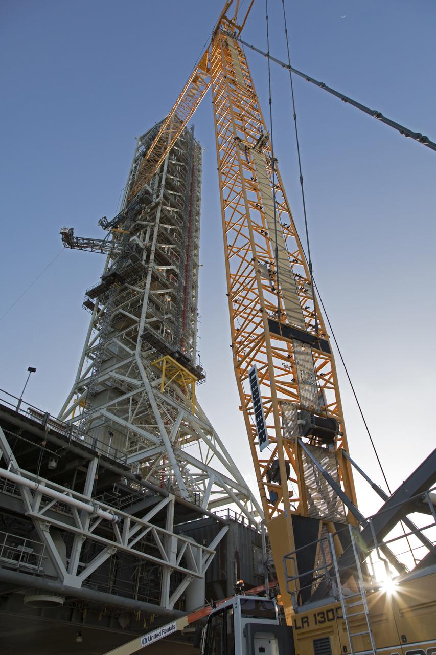 High up on the mobile launcher (ML) tower at NASA's Kennedy Space Center in Florida, construction workers assist as a crane moves the Core Stage Inter-tank Umbilical (CSITU) into place for a fit check of the attachment hardware. The CSITU will be located at about the 140-foot level of the ML tower. The umbilical will be lowered down and installed permanently on the ML at a later date. The CSITU is a swing-arm umbilical that will connect to the Space Launch System core stage inter-tank. It will provide conditioned air, pressurized gases and power and data connection to the core stage. The Ground Systems Development and Operations Program is overseeing installation of the umbilicals.