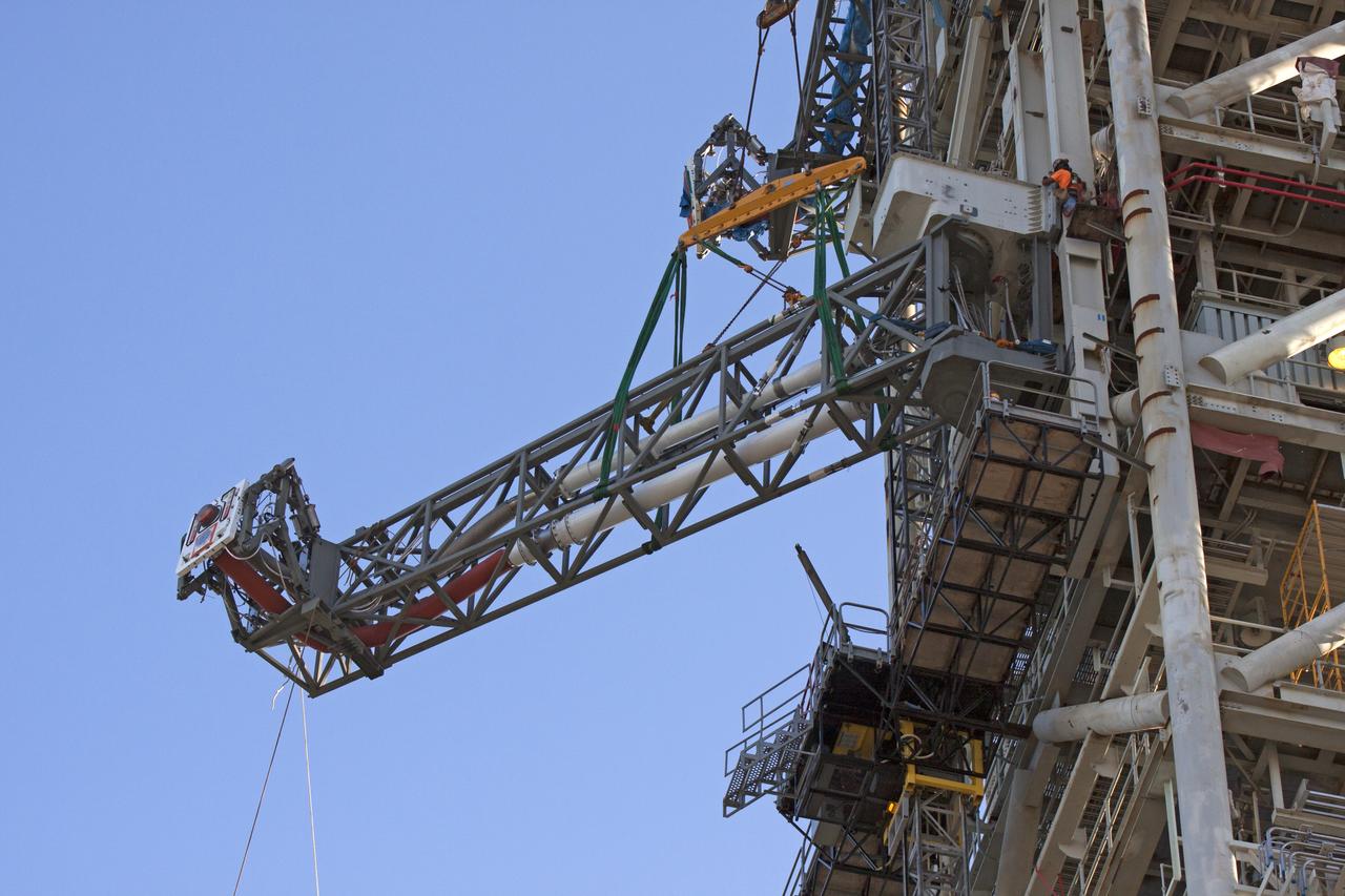 High up on the mobile launcher (ML) tower at NASA's Kennedy Space Center in Florida, construction workers assist as a crane moves the Core Stage Inter-tank Umbilical (CSITU) into place for a fit check of the attachment hardware. The CSITU will be located at about the 140-foot level of the ML tower. The umbilical will be lowered down and installed permanently on the ML at a later date. The CSITU is a swing-arm umbilical that will connect to the Space Launch System core stage inter-tank. It will provide conditioned air, pressurized gases and power and data connection to the core stage. The Ground Systems Development and Operations Program is overseeing installation of the umbilicals. 