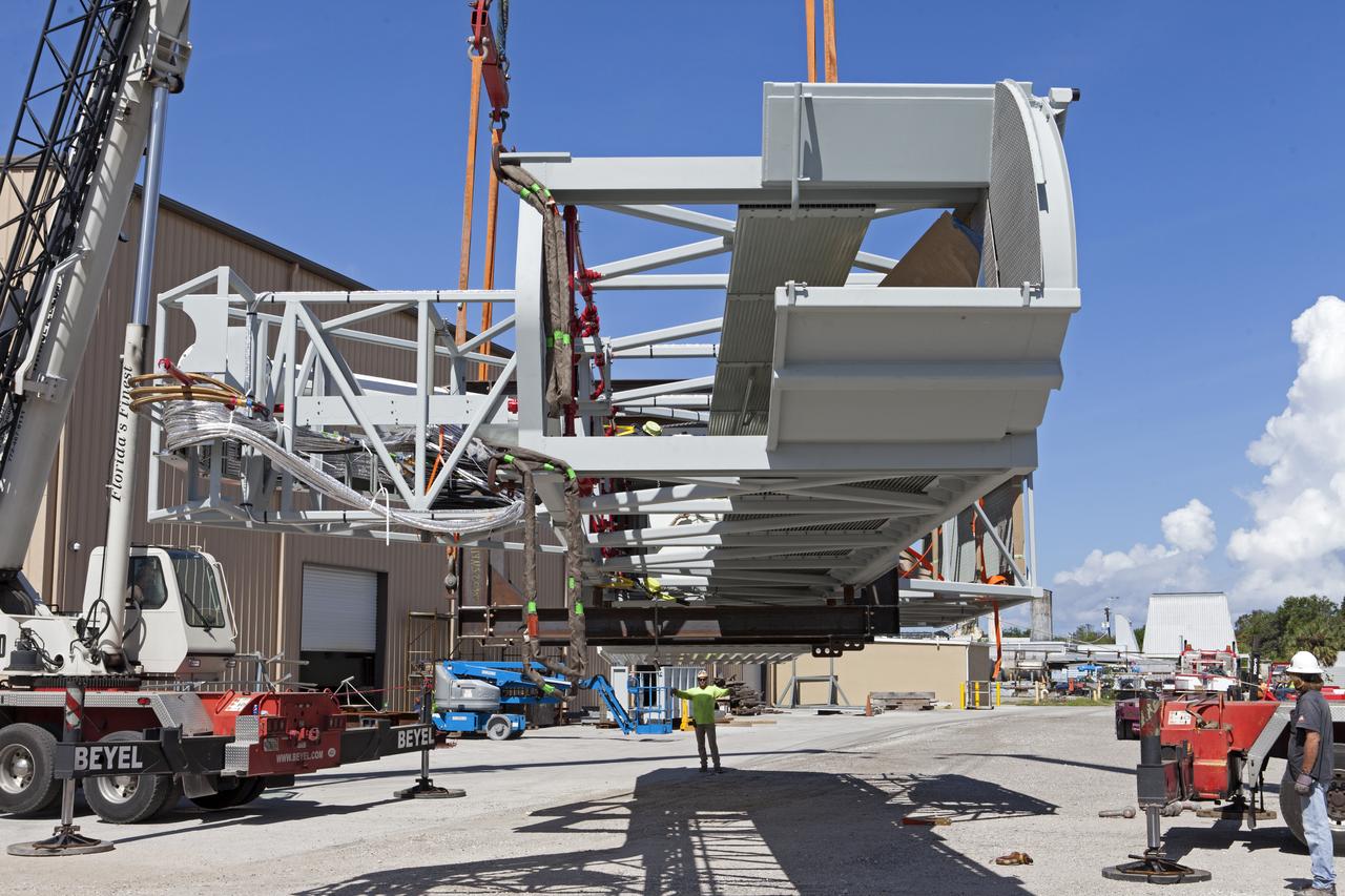 The Orion crew access arm is being moved by crane onto a flatbed truck at Precision Fabricating and Cleaning in Cocoa, Florida. The crew access arm will be transported to a storage location near NASA's Kennedy Space Center in Florida. Later this month, the arm will be transported to the mobile launcher (ML) tower at the center. The crew access arm will be located at about the 274-foot level on the tower. It will rotate from its retracted position and interface with the Orion crew hatch location to provide entry to the Orion crew module. The Ground Systems Development and Operations Program is overseeing installation of umbilicals and launch accessories on the ML tower. 