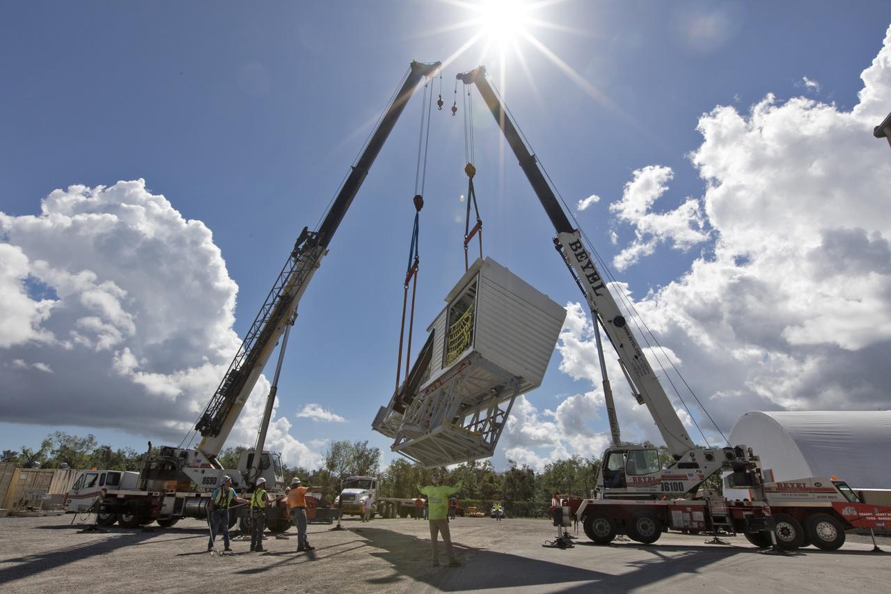 Two heavy-lift cranes are being used to move the Orion crew access arm and lower it onto a flatbed truck at Precision Fabricating and Cleaning in Cocoa, Florida. The crew access arm will be transported to a storage location near NASA's Kennedy Space Center in Florida. Later this month, the arm will be transported to the mobile launcher (ML) tower at the center. The crew access arm will be located at about the 274-foot level on the tower. It will rotate from its retracted position and interface with the Orion crew hatch location to provide entry to the Orion crew module. The Ground Systems Development and Operations Program is overseeing installation of umbilicals and launch accessories on the ML tower.
