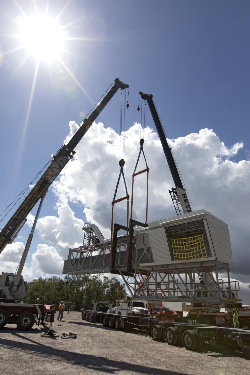 Two heavy-lift cranes are used to lower the Orion crew access arm onto a flatbed truck at Precision Fabricating and Cleaning in Cocoa, Florida. The crew access arm will be transported to a storage location near NASA's Kennedy Space Center in Florida. Later this month, the arm will be transported to the mobile launcher (ML) tower at the center. The crew access arm will be located at about the 274-foot level on the tower. It will rotate from its retracted position and interface with the Orion crew hatch location to provide entry to the Orion crew module. The Ground Systems Development and Operations Program is overseeing installation of umbilicals and launch accessories on the ML tower. 