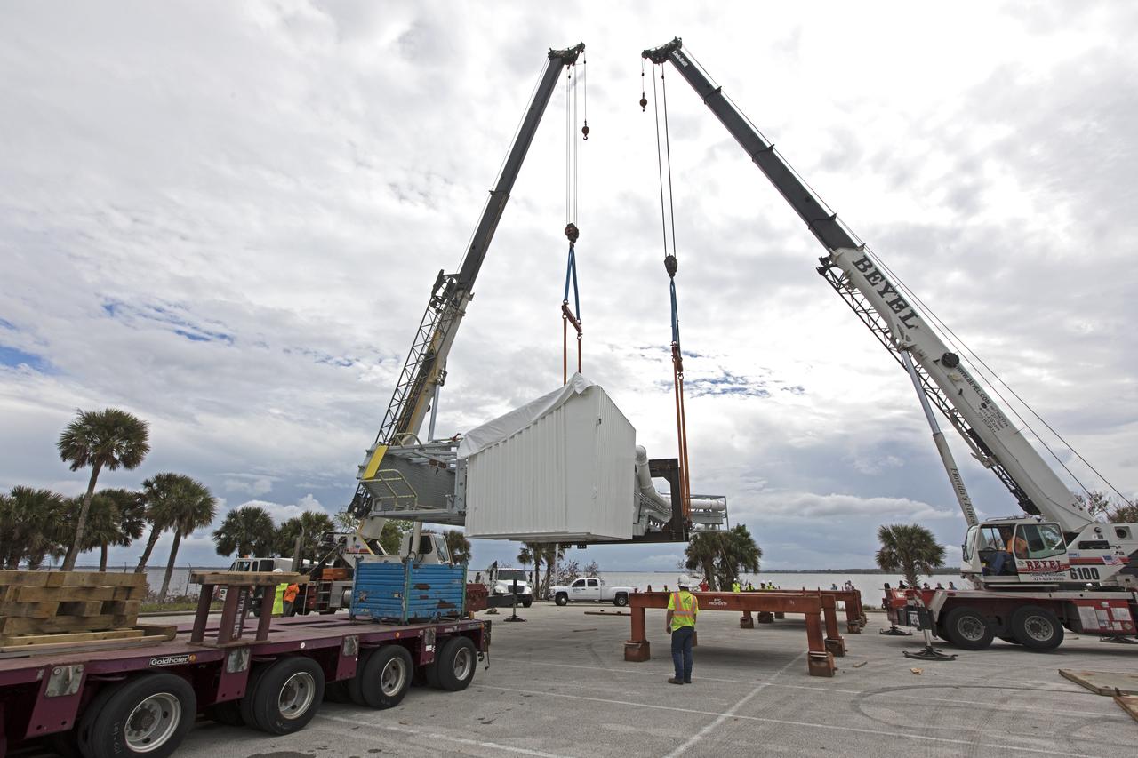 Two heavy-lift cranes are used to lift the Orion crew access arm up from a flatbed truck in a storage location at NASA's Kennedy Space Center in Florida. The access arm was transported from Precision Fabricating and Cleaning in Cocoa, Florida. Later this month, the arm will be transported to the mobile launcher (ML) tower at the center. The crew access arm will be located at about the 274-foot level on the tower. It will rotate from its retracted position and interface with the Orion crew hatch location to provide entry to the Orion crew module. The Ground Systems Development and Operations Program is overseeing installation of umbilicals and launch accessories on the ML tower. 