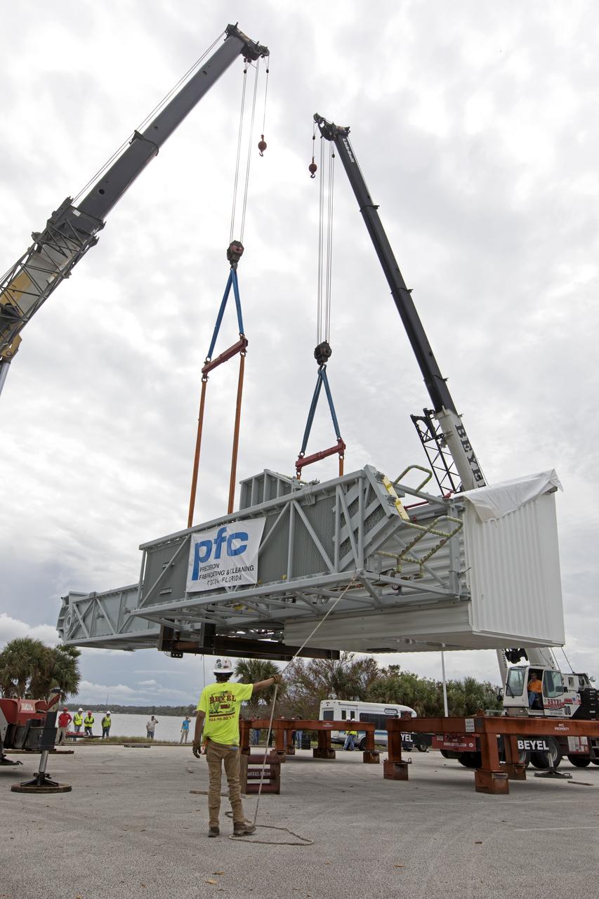 Two heavy-lift cranes are used to lower the Orion crew access arm onto a work stand in a storage location at NASA's Kennedy Space Center in Florida. The access arm was transported from Precision Fabricating and Cleaning in Cocoa, Florida. Later this month, the arm will be transported to the mobile launcher (ML) tower at the center. The crew access arm will be located at about the 274-foot level on the tower. It will rotate from its retracted position and interface with the Orion crew hatch location to provide entry to the Orion crew module. The Ground Systems Development and Operations Program is overseeing installation of umbilicals and launch accessories on the ML tower. 