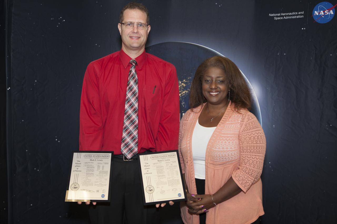 Mark Lewis displays the two U.S. Patent plaques he received during a ceremony at the 2017 Innovation Expo at NASA's Kennedy Space Center in Florida. To his right is Kelly Jones-McDowall, event co-chairperson. The purpose of the annual two-day expo is to help foster innovation and creativity among the Kennedy workforce. The event included several keynote speakers, training opportunities, an innovation showcase and the KSC Kickstart competition.